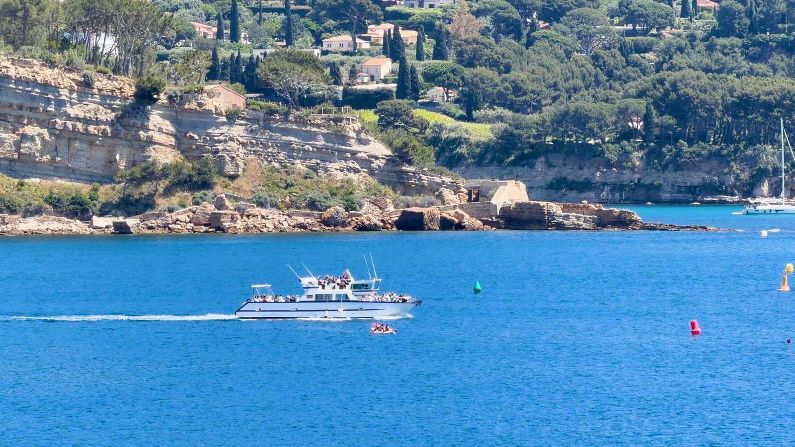 Barca bianca che costeggia una scogliera rocciosa